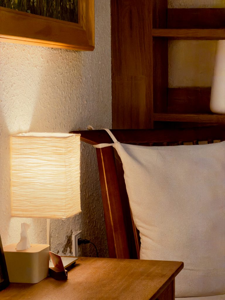 Warm bedside table lamp casting a soft glow beside a bed in a cozy bedroom