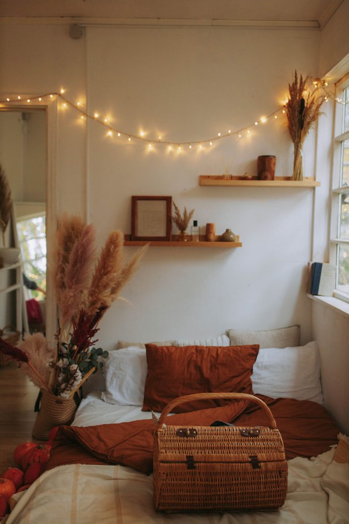 Warm string lights hanging above a cozy bed with earthy decor and woven accents.
