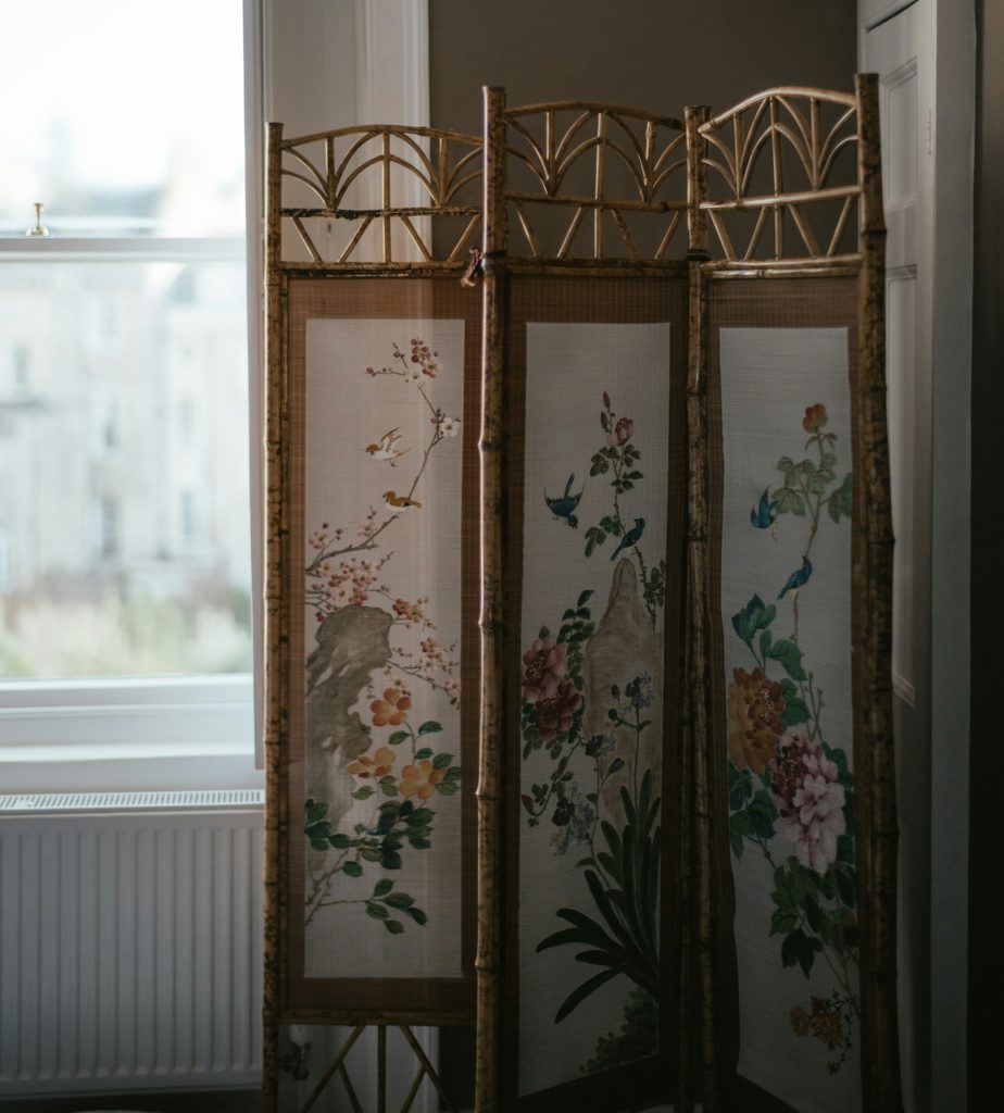 Vintage-inspired botanical folding screen with floral and bird illustrations, styled as a statement room divider for a Black Nouveau aesthetic interior.